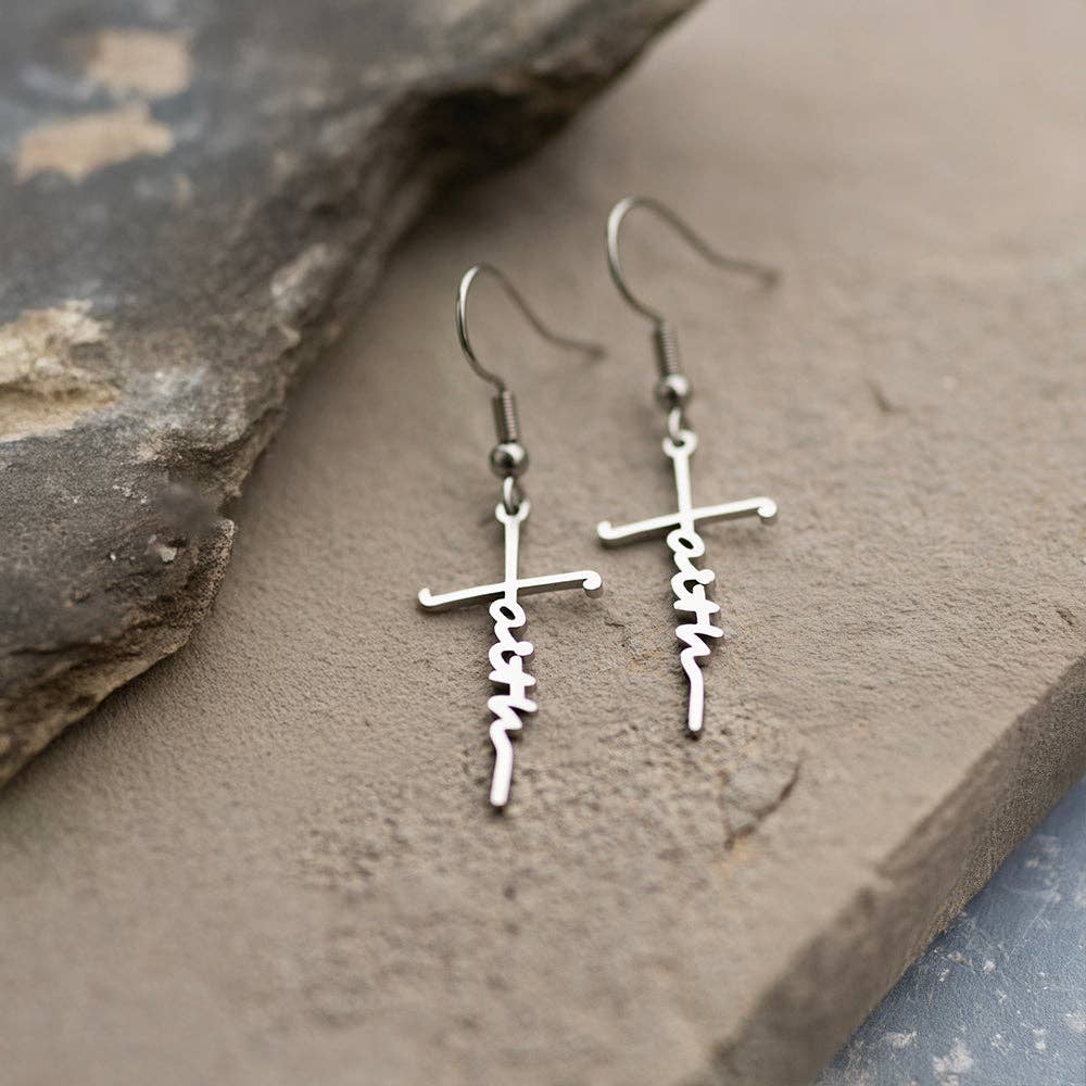 Silver cross-shaped earrings with 'faith' inscription on stone surface